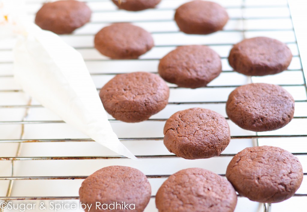 For the Chocolate Cookies • Softened Butter, ½ cup or 100 grams approx. • Powdered White Sugar, ½ cup • Dark Brown Sugar, ½ cup or 100 grams approx. • Egg, 1 (substitute in notes) • Vanilla Essence, 1 teaspoon • All Purpose Flour (Maida), 1 cup or 130 grams approx. • Baking Powder, 1 teaspoon • Cocoa Powder, ⅔rd cup or 75 grams approx. • Salt, ¼ teaspoon • Milk, 3 tablespoons For the Filling • Icing Sugar, 1 ½ cup or 165 grams • Unsalted Butter (or White Butter), ½ cup or 100 grams • Vanilla Essence, 1 teaspoon For the Chocolate Cookies • Softened Butter, ½ cup or 100 grams approx. • Powdered White Sugar, ½ cup • Dark Brown Sugar, ½ cup or 100 grams approx. • Egg, 1 (substitute in notes) • Vanilla Essence, 1 teaspoon • All Purpose Flour (Maida), 1 cup or 130 grams approx. • Baking Powder, 1 teaspoon • Cocoa Powder, ⅔rd cup or 75 grams approx. • Salt, ¼ teaspoon • Milk, 3 tablespoons For the Filling • Icing Sugar, 1 ½ cup or 165 grams • Unsalted Butter (or White Butter), ½ cup or 100 grams • Vanilla Essence, 1 teaspoon